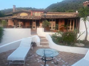 Esclusiva villa sul mare Tropea في بارغيليا: منزل به فناء مع كرسيين وطاولة