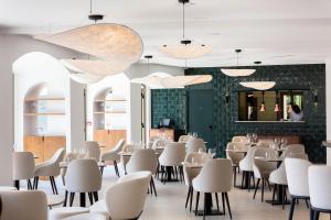 a dining room with white chairs and tables at Hôtel du Parc Cavalaire sur Mer in Cavalaire-sur-Mer