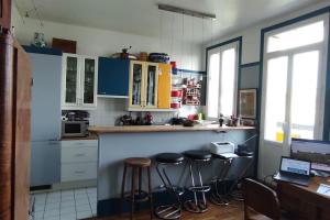 una cocina con taburetes y armarios azules y blancos en Logement entier, vue, Paris centre, Catacombes en París