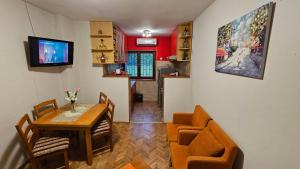 a dining room with a table and chairs and a television at Vila Lena Banja Vrujci in Berkovac
