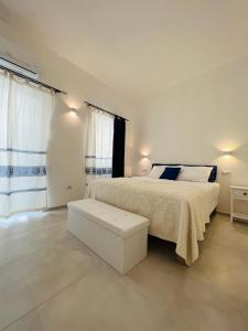 um quarto branco com uma cama e um banco em Via Giardini Rooms em Villasimius