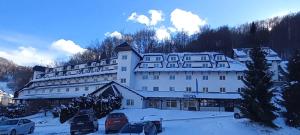 a large white building with cars parked in the snow at Brzeće-GONDOLA 100m in Brzeće