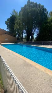 a large blue swimming pool next to a fence at Joli Appartement 27m2 Oasis Provençale en village vacances en Camargue in Arles