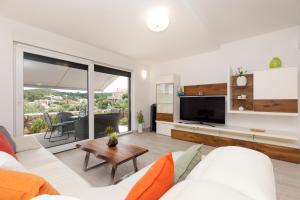 a living room with a white couch and a tv at Apartments Tony in Mali Lošinj