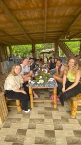 een groep mensen die aan een tafel zitten bij Meadow Mai Chau Homestay in Mai Chau