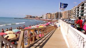 una playa con un montón de gente con sombrillas en Playa los loco, en Torrevieja