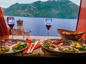 un tavolo con due piatti di cibo e due bicchieri di vino di Casa Savia, vacanze lago d'Iseo a Pisogne
