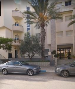 twee auto's geparkeerd op een parkeerplaats voor een gebouw bij Cozy Inn Lac 2 in Tunis