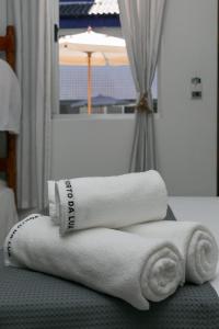 een stapel handdoeken bovenop een bed bij Hotel Pousada Porto da Lua in Guaratuba