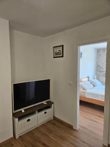 a living room with a flat screen tv and a bed at APARTMAN ELI in Supetar