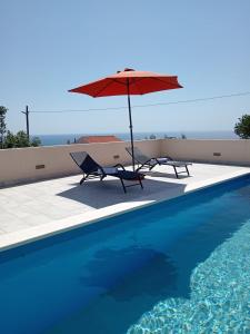 2 sillas y sombrilla junto a la piscina en Villa Daria, en Sevid