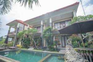 un bâtiment avec une piscine en face d'une maison dans l'établissement Adipana Bungalow-Balinese Room, à Ubud