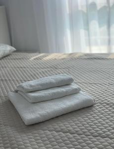 3 toallas sentadas encima de una cama en Apartament Grand Hill 1, en Oradea
