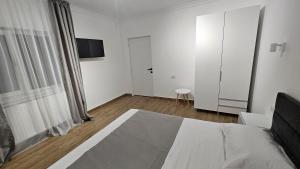 a white bedroom with a bed and a tv at Nord 22 in Constanţa