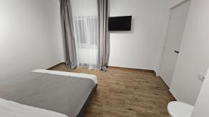 um pequeno quarto branco com uma cama e uma televisão em Nord 22 em Constança