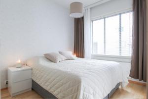 een witte slaapkamer met een bed en een raam bij City Apartment Satamantupa in Kuopio