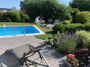 un patio con piscina y algunas sillas y flores en Maudon Coeur de Baie, en Ponts