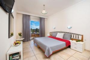 een slaapkamer met een bed, een televisie en een balkon bij Kavos Plaza Hotel in Kavos