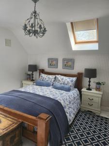 a bedroom with a bed with blue sheets and a chandelier at Faithlegg Hotel Lodge in Waterford