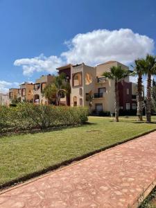 een gebouw met palmbomen en een pad in een park bij Appartement en résidence + grande terrasse sur le toit in Saidia 