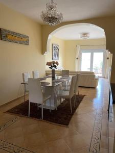 a dining room with a table and chairs and a couch at Appartement en résidence + grande terrasse sur le toit in Saidia 