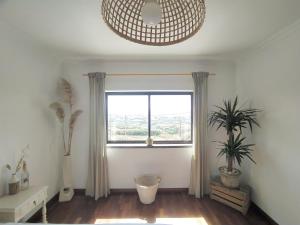 uma sala de estar com uma janela e um vaso de plantas em Villa Intuitiva na Lourinhã