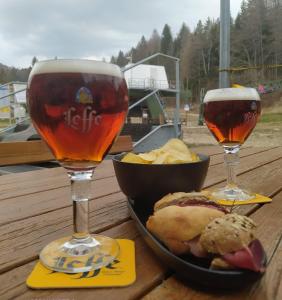 due bicchieri di birra e una ciotola di cibo su un tavolo di legno di Casetta Maia a Lavarone