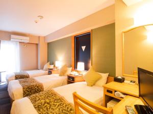 a hotel room with two beds and a television at Hotel AreaOne Kushiro in Kushiro