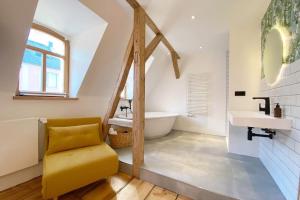 a bathroom with a yellow chair and a tub and sink at Zentrale 1-Zimmer-Ferienwohnung mit digitalem Check in in Hof