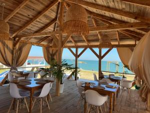 a restaurant with tables and chairs and the beach at Апартаменты Denis in Gudauta