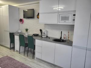a kitchen with white cabinets and green chairs at Garsoniera Ady in Mangalia