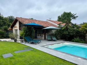 un patio trasero con piscina y una casa en O'PINTXO, en Onesse-et-Laharie