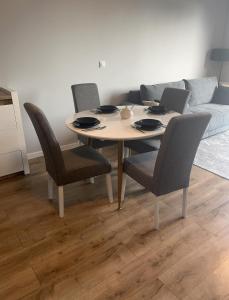 a dining room table with chairs and a couch at Apartament Nowoczesny w Centrum Torunia/podziemny parking i winda in Toruń