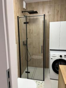 a shower in a bathroom with a washing machine at Apartament Nowoczesny w Centrum Torunia/podziemny parking i winda in Toruń