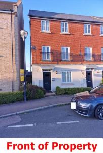 a car parked in front of a brick building at NightRest Homes 6 Bedroom House- Smart TV In each Room - Parking - Wifi in Milton Keynes
