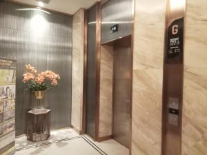 een lift in een gebouw met een vaas met bloemen bij Apartement Studio Pollux Habibi Batam A13712 in Batam Center