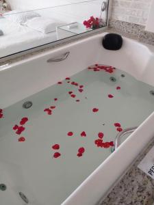 a bath tub with red flowers on the floor at Felicidade in front sea in Saquarema