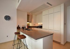 a kitchen with white cabinets and a counter with stools at Marina Gate Modern & Unique 1 Bed by AirDHP in Dubai