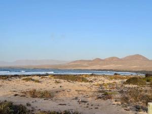 una playa con el océano y las montañas en el fondo en El descanso de Bielo Lanzarote, en Caleta de Caballo