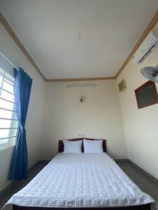 1 dormitorio con 1 cama grande y cortina azul en Khách sạn Ban Mê Xanh (Ban Me Xanh Hotel), en Buon Ma Thuot