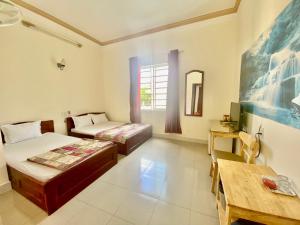 1 dormitorio con 2 camas, escritorio y mesa en Khách sạn Ban Mê Xanh (Ban Me Xanh Hotel), en Buon Ma Thuot