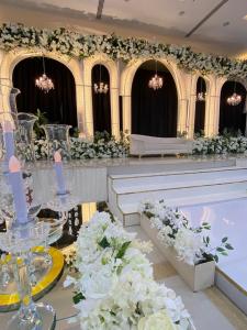 a banquet hall with white flowers and white benches at Al Ayjah Plaza Hotel in Sur