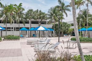 um pátio com guarda-sóis e cadeiras azuis e brancas e palmeiras em OCEAN RESERVE APARTMENt em Miami Beach