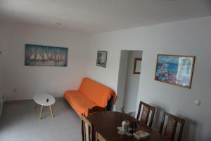a living room with an orange couch and a table at Apartments Lučin in Drvenik Veli