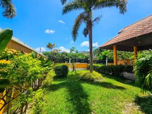 a yard with palm trees and a building at The Orange Villa Near Beach 海灘附近的家庭別墅 in Kamala Beach