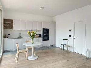 a white kitchen with a table and a vase of flowers at #2800ourhome 201 in Mechelen