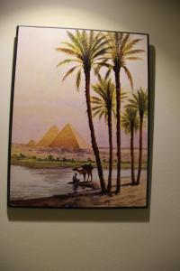 a painting of palm trees and a man with a camel and the pyramids at Miramar Downtown in Cairo