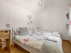 a bedroom with two beds and a chandelier at Little Tree Cottage in Felmingham