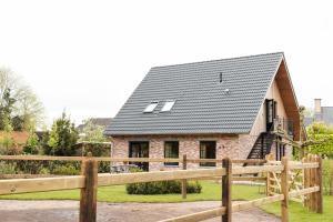ein Haus mit einem schwarzen Dach und einem Holzzaun in der Unterkunft Vakantiehoeve 'De Zandrug' in Stekene