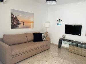 a living room with a couch and a flat screen tv at Asterias Studios in Adamantas